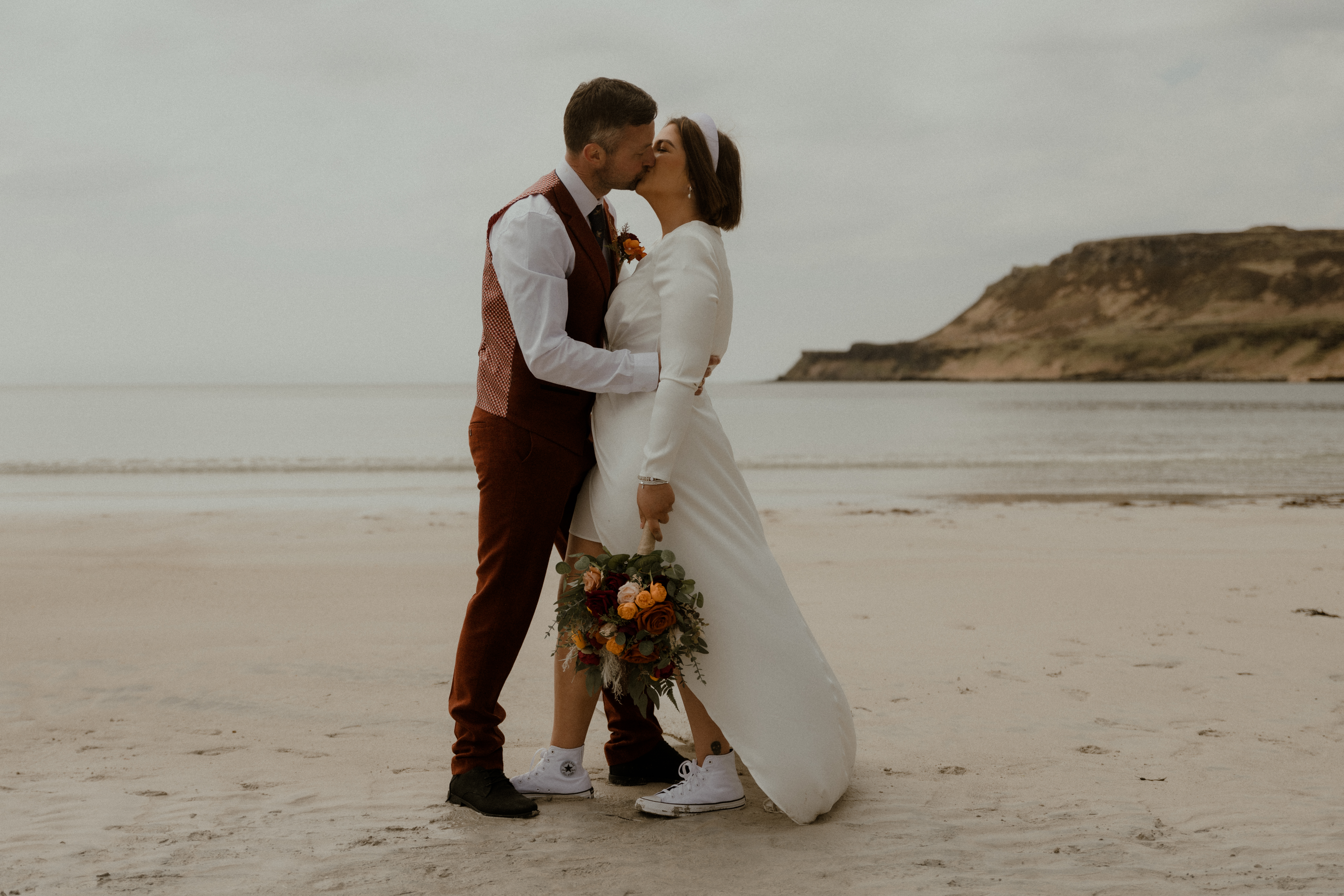 wedding couple kissing on the isle of mull with the sea in the background