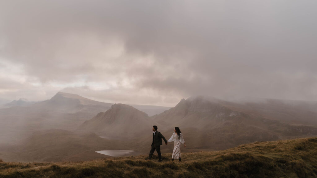 Couple walking hand in hand during an Isle of Skye couples photoshoot on the Quiraing, captured by Scotland fine art photographer Aly Robinson.