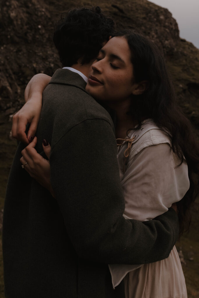Emotional embrace during a cinematic Isle of Skye couples session, photographed on the Quiraing with moody Scottish landscape tones.
