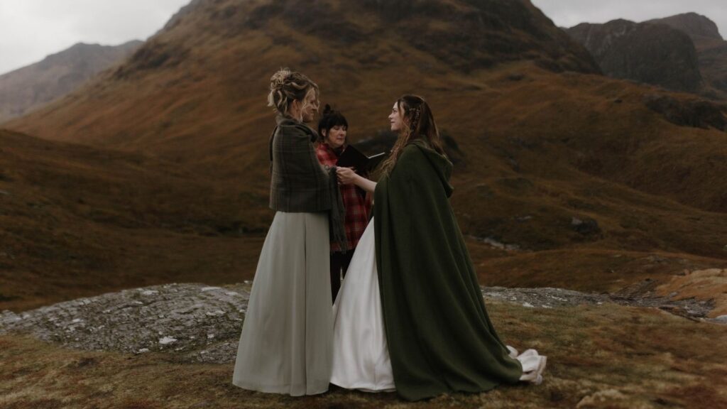 LGBTQ+ couple exchanging vows during their Glencoe elopement at Buachaille Etive Beag, photographed by Aly Robinson Photography in the Scottish Highlands.