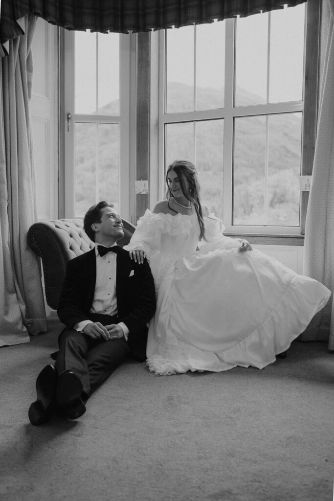 Romantic cinematic portrait of a newly married couple sitting on the floor by a large window with soft natural light, captured by Scotland wedding photographer Aly Robinson.”