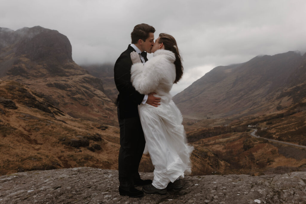 Moody Scotland elopement couple kissing in Glencoe, captured by a cinematic Highlands wedding photographer Aly Robinson with a dark romance aesthetic.