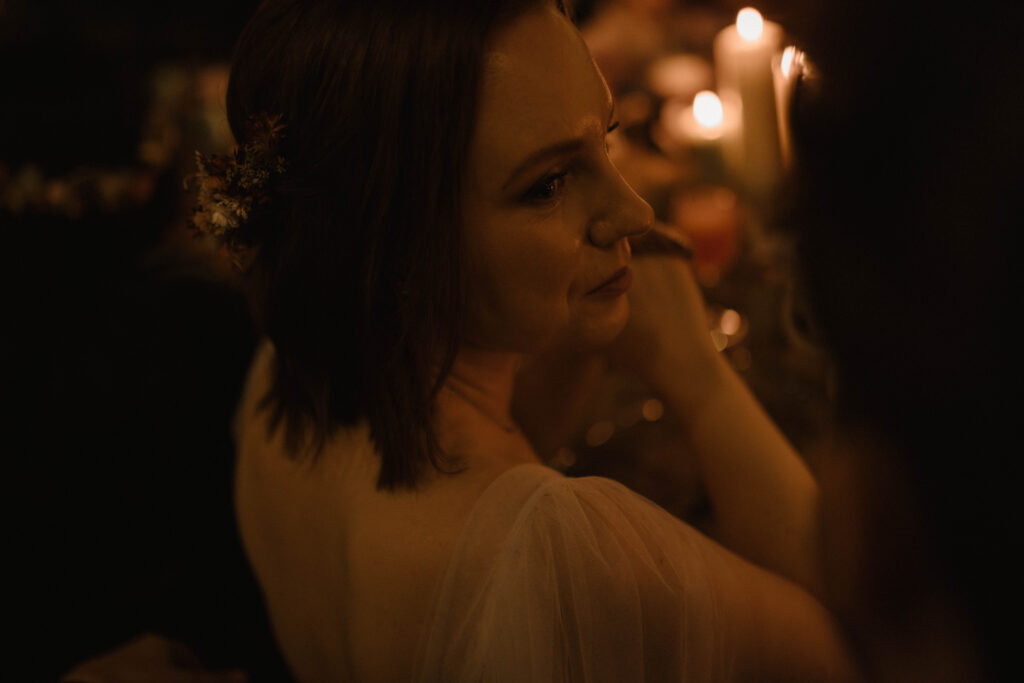 Emotional close-up portrait of a bride surrounded by candlelight during an intimate wedding dinner, photographed by Scotland wedding photographer Aly Robinson.
