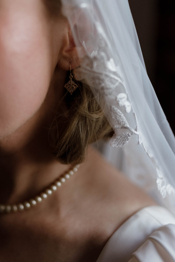 Close-up bridal detail of veil lace, pearl necklace, and soft skin tones, captured in Aly Robinson’s signature cinematic style as a Scotland wedding photographer.
