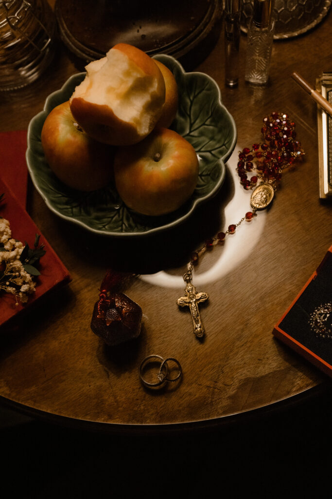 Moody wedding flat lay with rings, rosary, apples and candlelight styled details for gothic luxury wedding photography at Prestonfield House Edinburgh