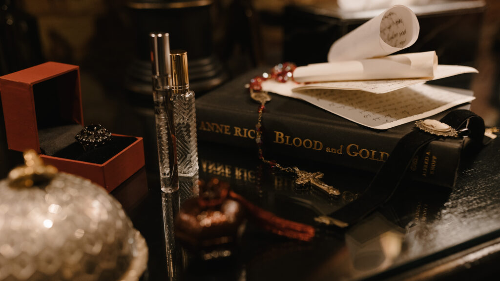 Still life wedding details at Prestonfield House Edinburgh featuring Anne Rice’s Blood and Gold novel, antique jewellery, perfume bottles and gothic styling for a cinematic luxury wedding shoot