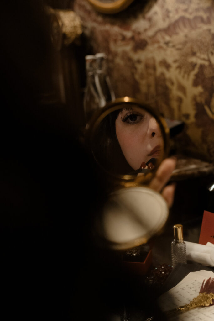 Close up reflection of bride in handheld mirror with vintage jewellery and perfume for cinematic editorial wedding photography at Prestonfield House Edinburgh
