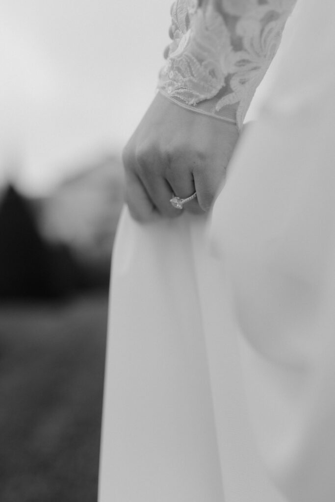 Black and white close up of bride’s hand with engagement ring and silk wedding dress detail for fine art wedding photography in Edinburgh