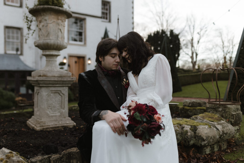 Bride and groom embracing in the gardens of Prestonfield House Edinburgh during a dark romance inspired luxury wedding photography session at sunrise