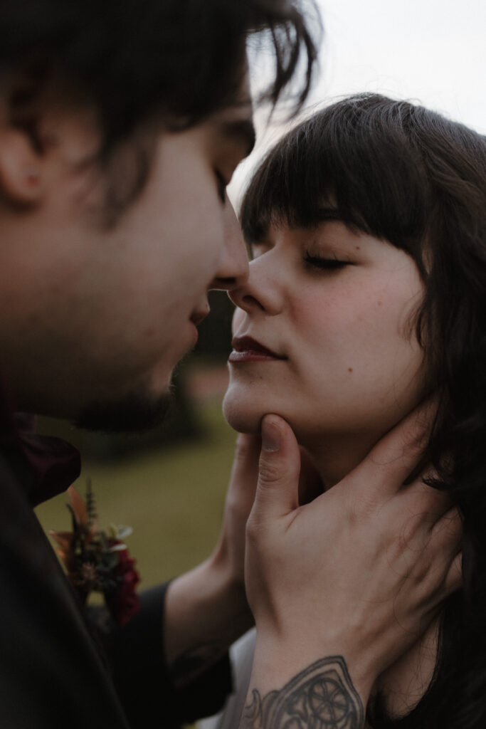 Bride and groom embracing with vintage cameo choker detail during dark romance inspired couple portrait at Prestonfield House Edinburgh