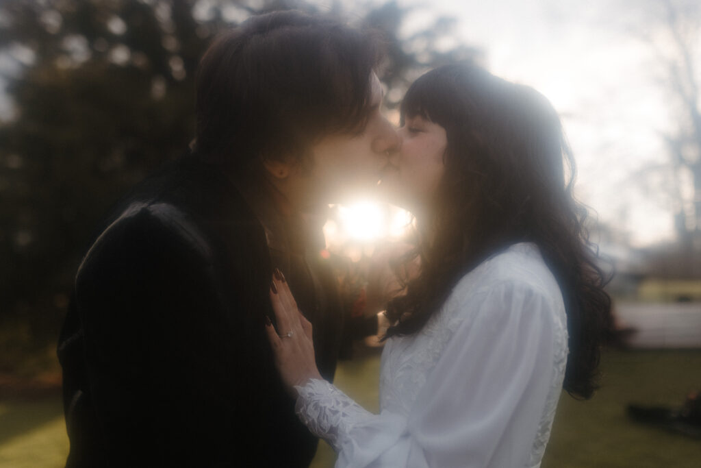 Couple kissing in soft sunset light outdoors at Prestonfield House Edinburgh photographed in a cinematic luxury wedding style