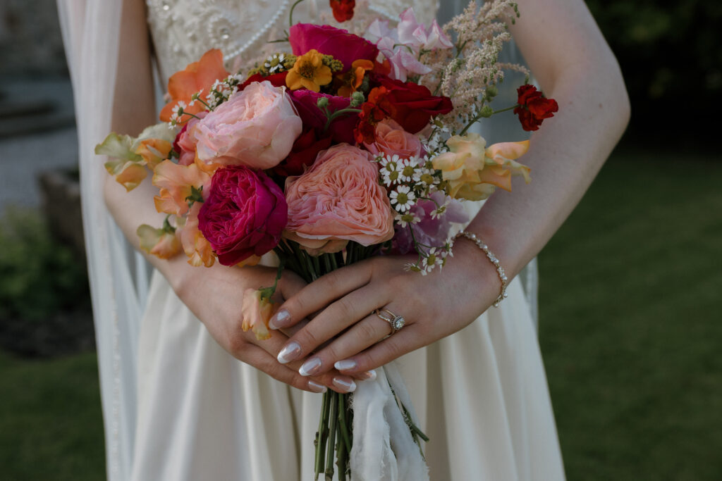 Colourful bridal bouquet at a rustic Dalduff Farm wedding near Glasgow with pink, orange and red summer flowers
